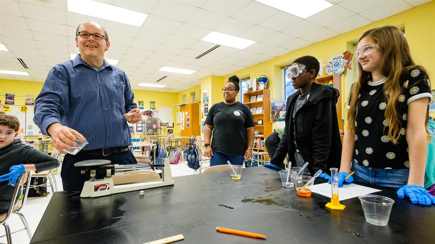 Josh Hunter smiles while helping his Moore Square Middle School students with an experiment 